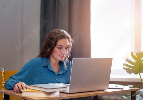 Attractive young woman is working on her laptop computer at home. Freelancer concept. Free Download Attractive young woman is working on her laptop computer at home. Freelancer concept. - GFXLoad