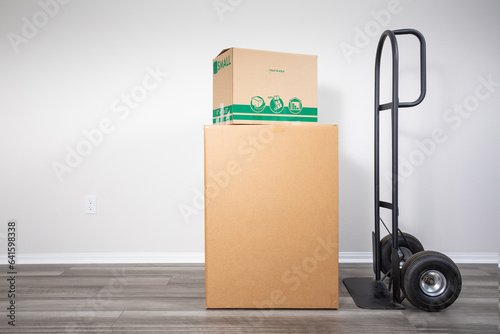 Cardboard moving boxes on hand truck indoors, ready for transportation. photo