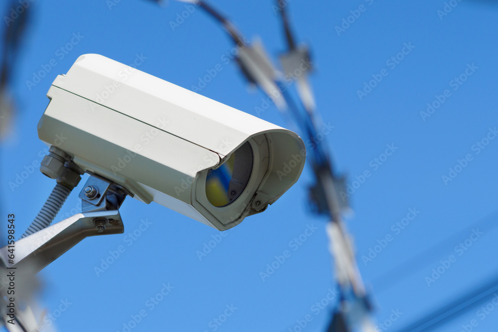 Outdoor surveillance camera against blue sky. View from bottom to top. Object security.