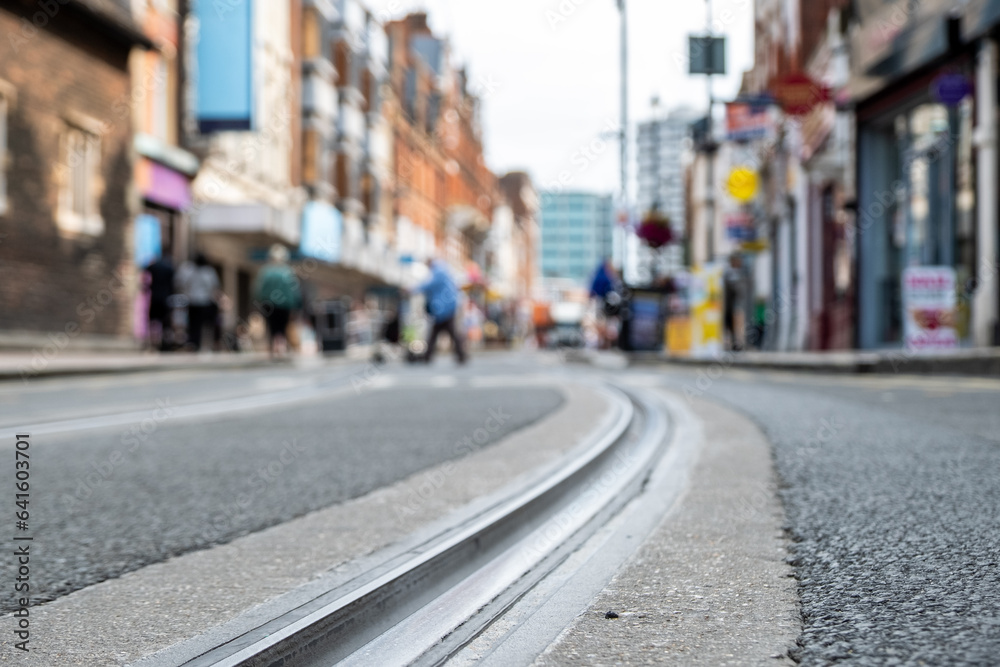 British high street shops close focused in tram tracks on the road- Croydon, South London