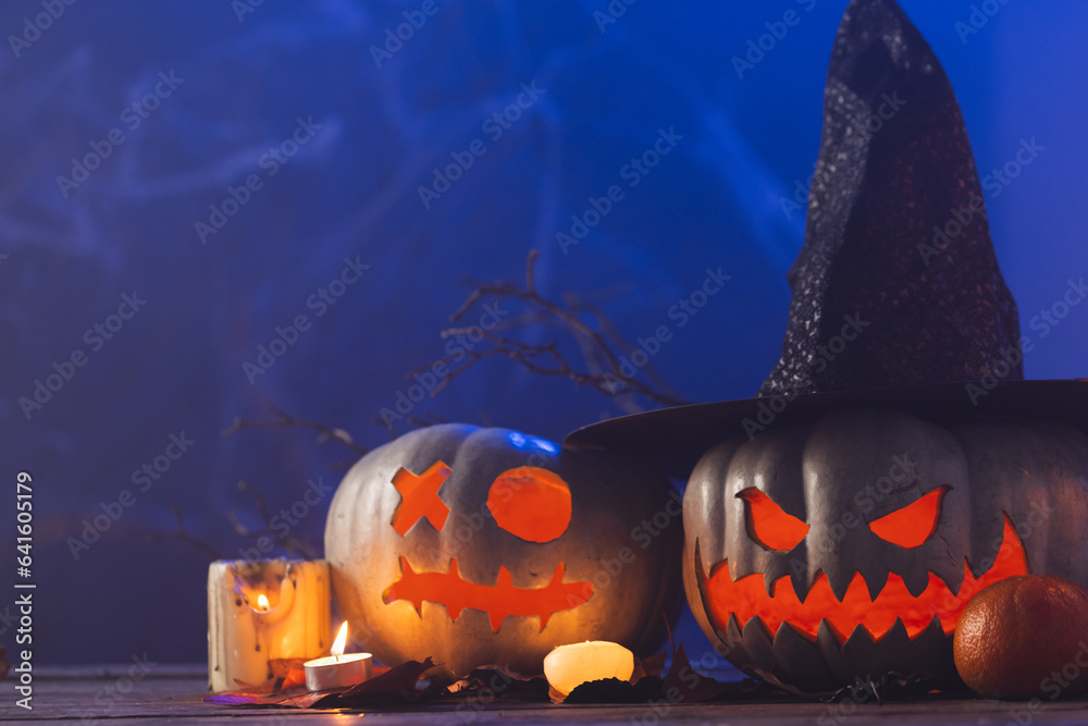 Fototapeta premium Carved pumpkins and candles with copy space on blue background