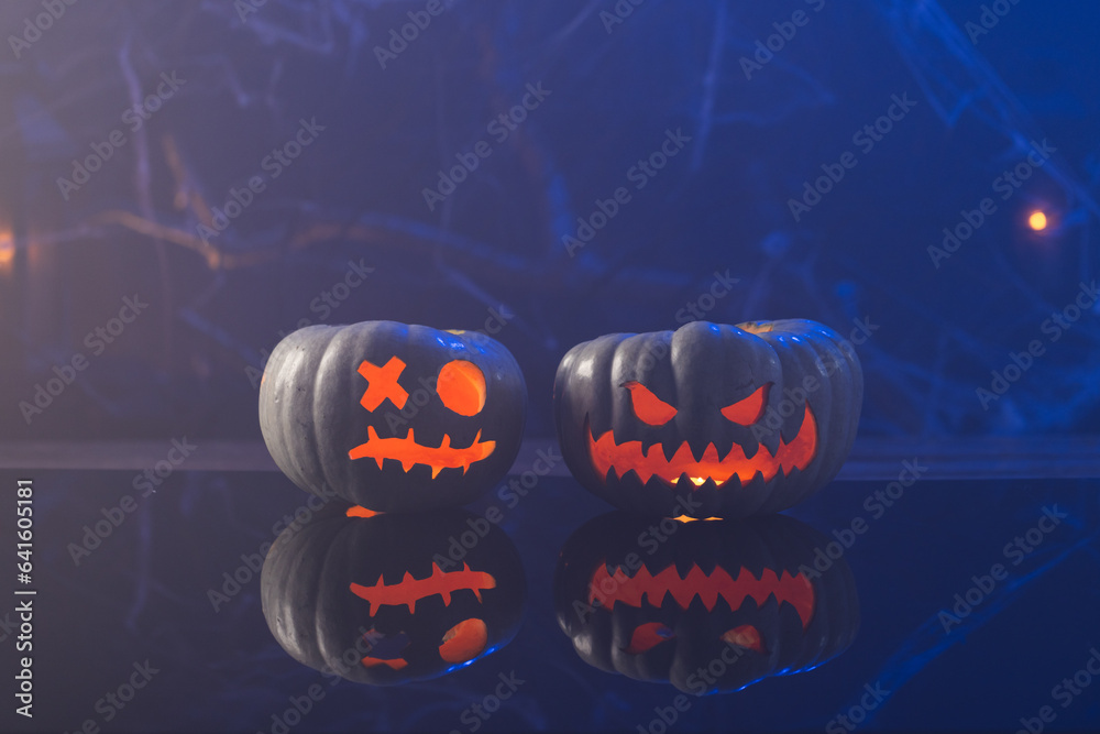 Fototapeta premium Carved pumpkins with copy space on blue background