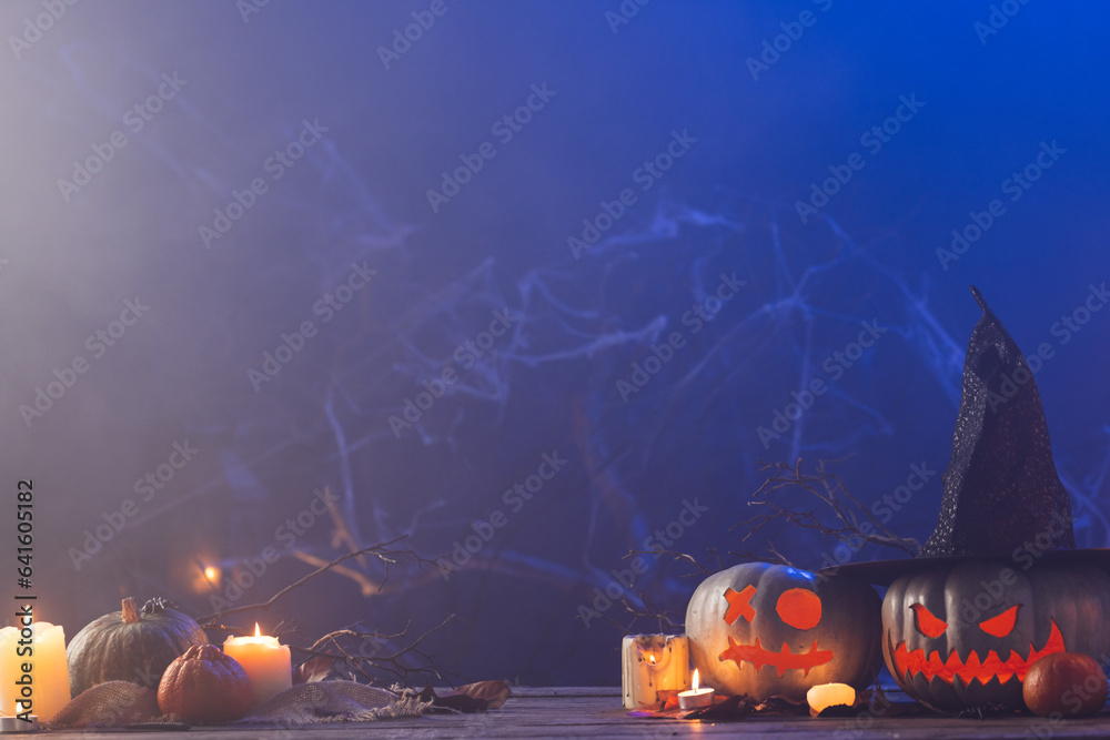 Fototapeta premium Carved pumpkins and candles with copy space on blue background
