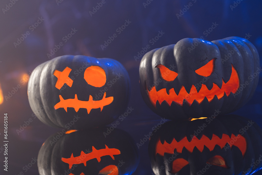 Fototapeta premium Two black carved pumpkins faces on blue background