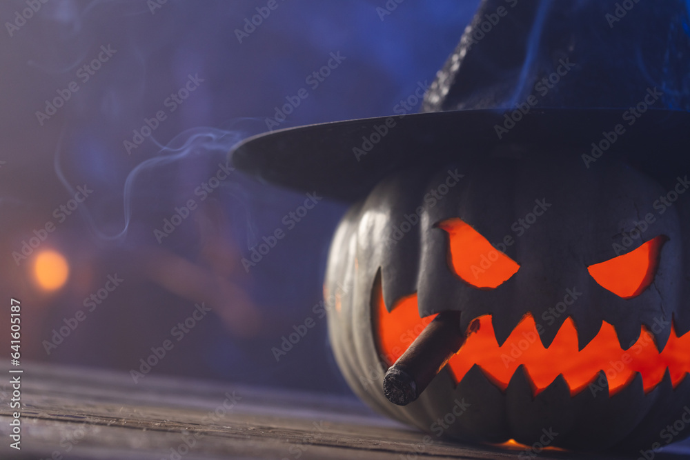 Fototapeta premium Carved pumpkin wearing witch hat with copy space on blue background