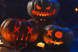 Three carved pumpkins and candle on black background
