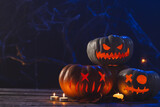 Three carved pumpkins and candles with copy space on black background