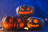 Three carved pumpkins and candles on blue background