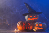 Three carved pumpkins and candles with copy space on blue background