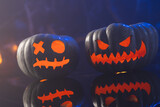 Two black carved pumpkins faces on blue background