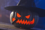 Carved pumpkin wearing witch hat on blue background