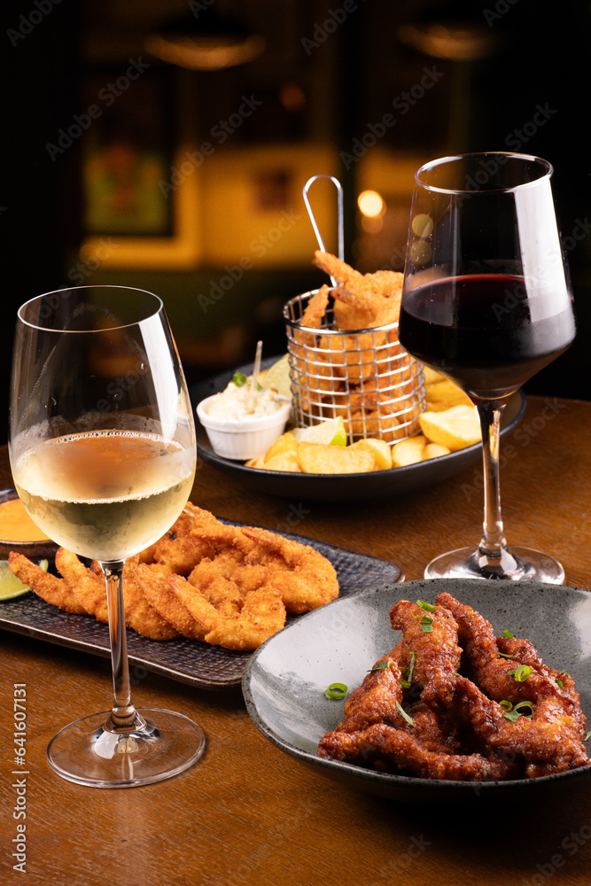 happy hour table in pub with two glasses of white and red wine and assorted portions of finger food blurred background happy hour table in pub with two glasses of white and red wine and assorted portions of finger food blurred background