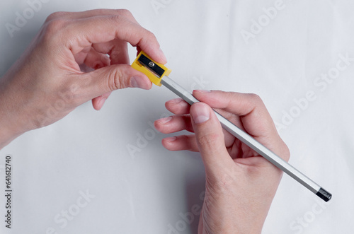 Pencil sharpening. Female hands with pencil and sharpener