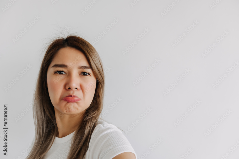 Unhappy Asian Thai women looking at camera with dislike and bored face, isolated over white background wall. Unhappy Asian Thai women looking at camera with dislike and bored face, isolated over white background wall.