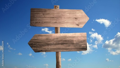 Blank wooden forked road directional sign over sunny sky