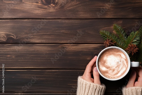 Female hands holding a cup of hot chocolate with cocoa powder on wooden background