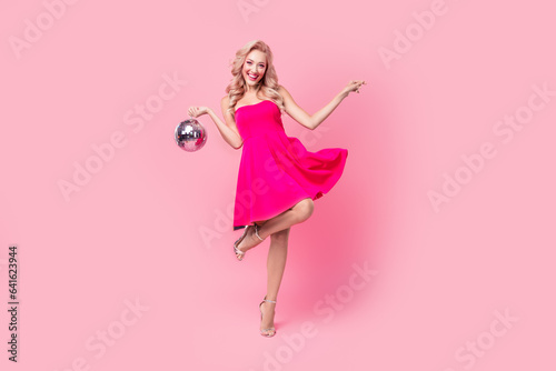 Full length photo of adorable carefree lady wear sexy dress having fun rising disco ball isolated pink color background
