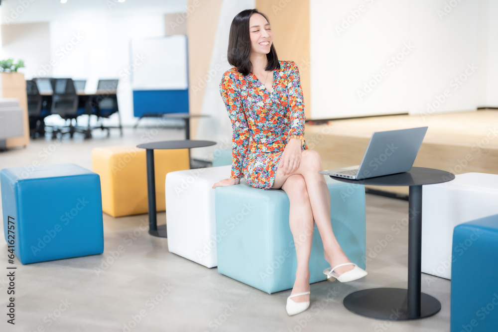 Asian female executive with short hair company head Wear a floral suit happy laugh There is a laptop for doing business work on the sofa. in office space There is a large monitor at the back. Asian female executive with short hair company head Wear a floral suit happy laugh There is a laptop for doing business work on the sofa. in office space There is a large monitor at the back.