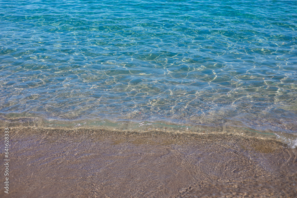 Transparent mediterranean warm sea waves and sand in sunny day closeup Transparent mediterranean warm sea waves and sand in sunny day closeup