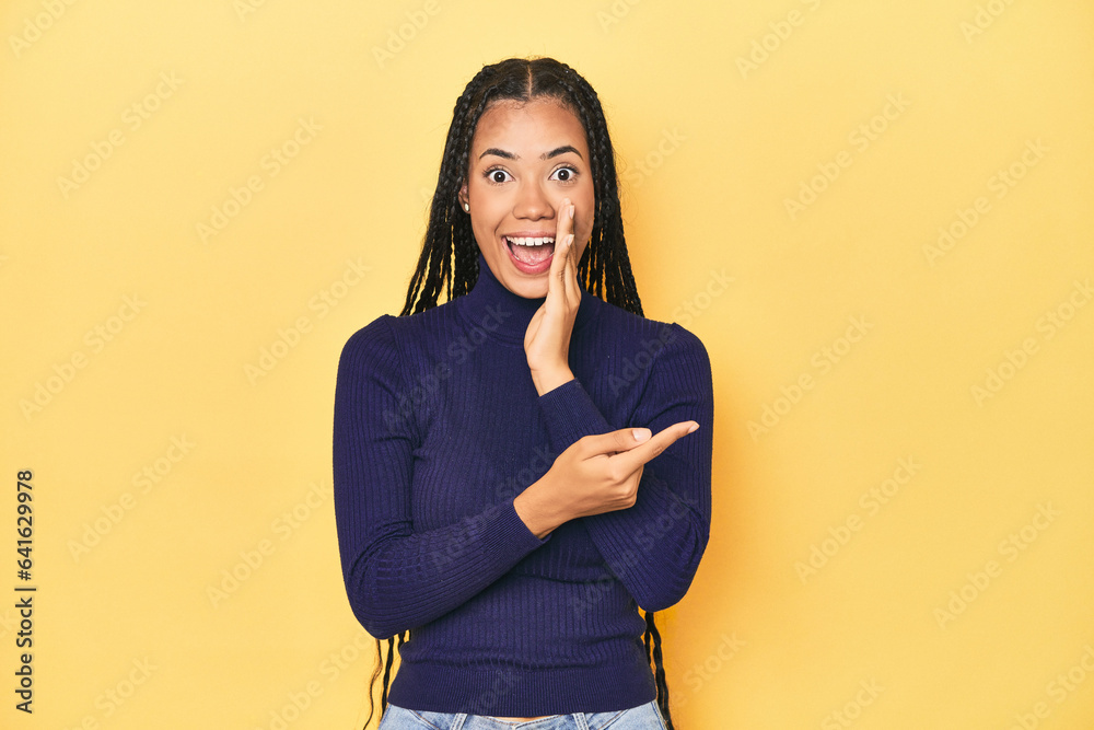Young Indonesian woman on yellow studio backdrop saying a gossip, pointing to side reporting something. Young Indonesian woman on yellow studio backdrop saying a gossip, pointing to side reporting something.
