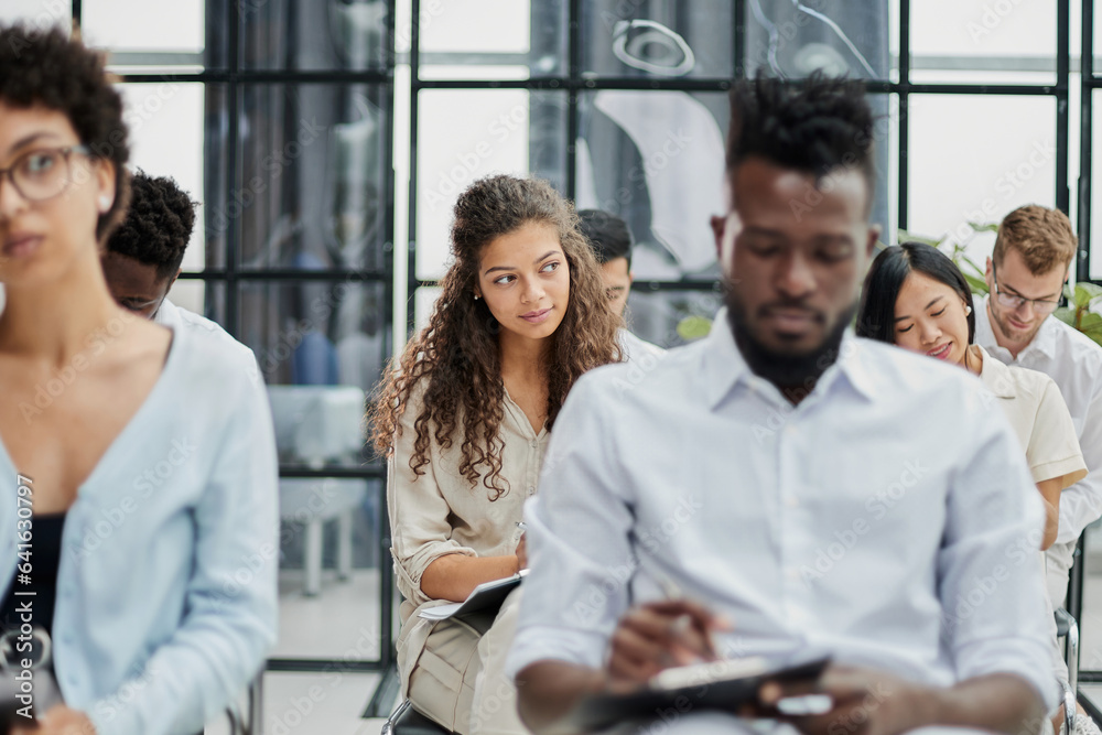 Multi-ethnic group of people while answering questions during training seminar or business conference in office, copy space Multi-ethnic group of people while answering questions during training seminar or business conference in office, copy space