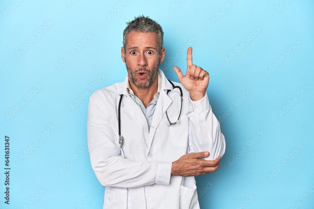 Caucasian middle-aged doctor on blue background having some great idea, concept of creativity. Caucasian middle-aged doctor on blue background having some great idea, concept of creativity.