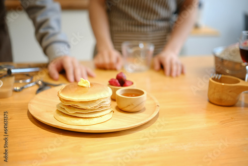 Tasty homemade pancakes with butter and maple syrup on wooden plate