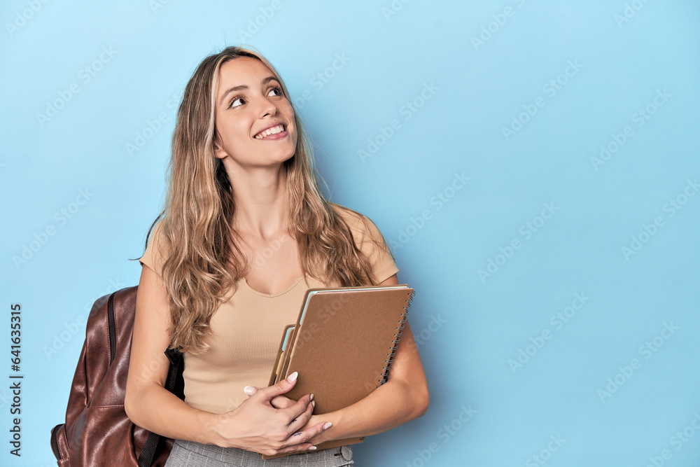 Fototapeta premium Blonde student with notebooks in blue studio