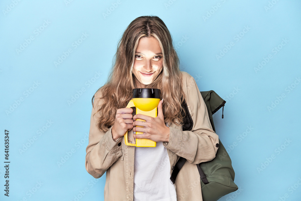 Traveler with backpack and flashlight in blue studio Traveler with backpack and flashlight in blue studio