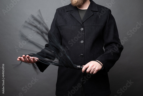 male dominant holds a leather whip Flogger for hard BDSM sex with spanking photo