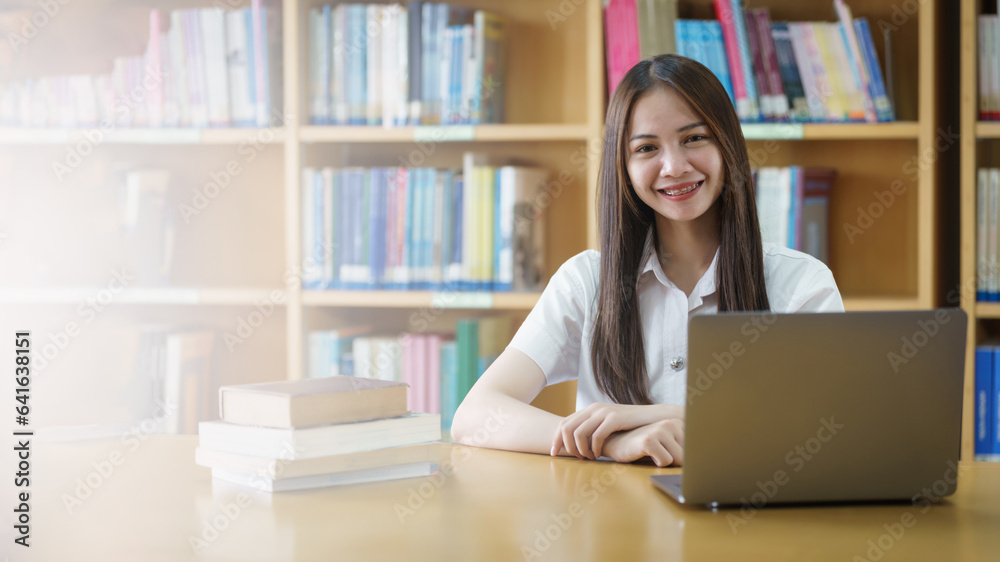 Portrait of an Asian girl college student studying in library doing project assignment and preparing for examination Portrait of an Asian girl college student studying in library doing project assignment and preparing for examination