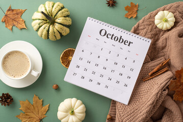 Welcoming autumn spirit. Top view shot featuring calendar with October month, sweater, steaming coffee, raw pattypans, cinnamon sticks, anise and more on green backdrop