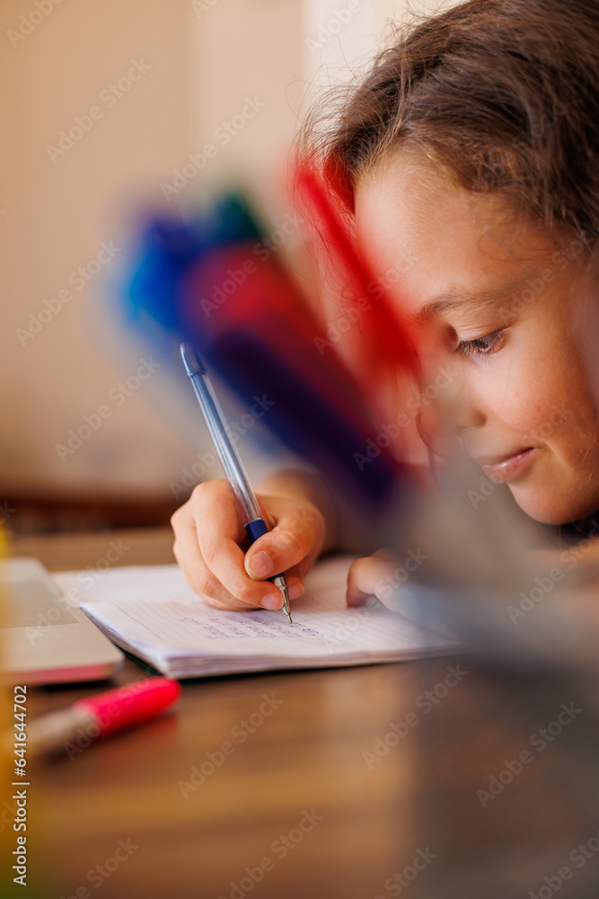 Children's hand close-up. the child uses a pencil to practice writing letters. The child learns to write in a notebook. Children's hand close-up. the child uses a pencil to practice writing letters. The child learns to write in a notebook.