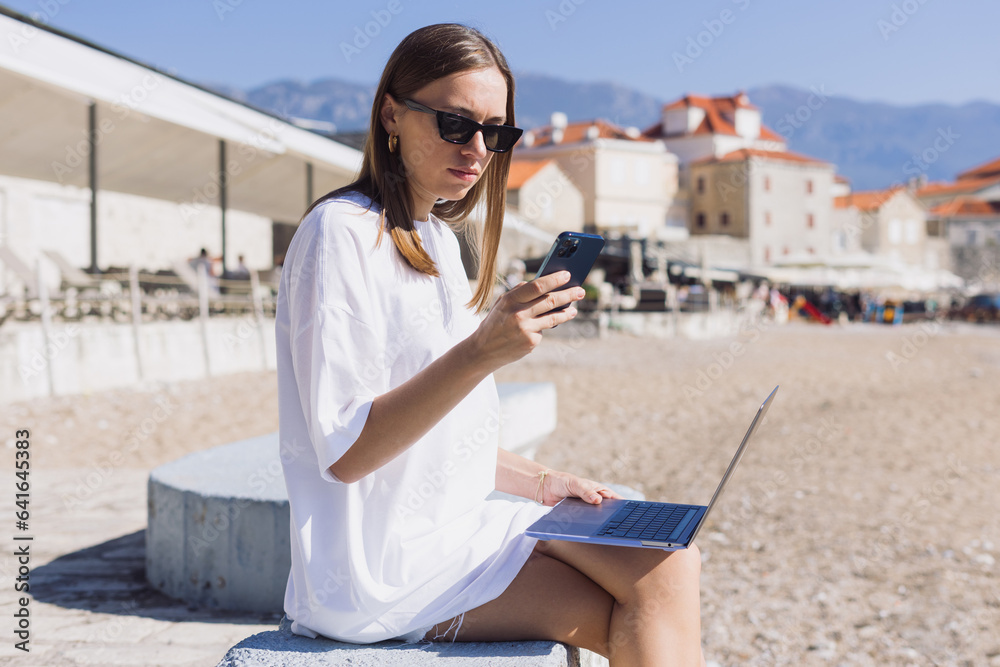 A businesswoman types on her phone during morning work by the sea. Remote personnel management