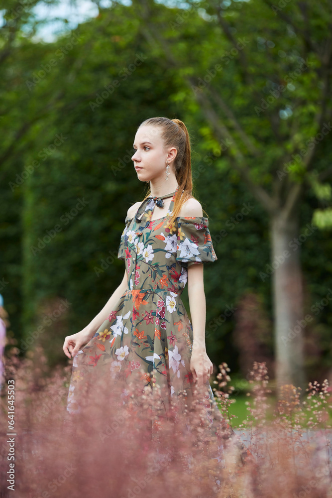 Beautiful young girl in the park. Bright green vegetation and red grass Beautiful young girl in the park. Bright green vegetation and red grass