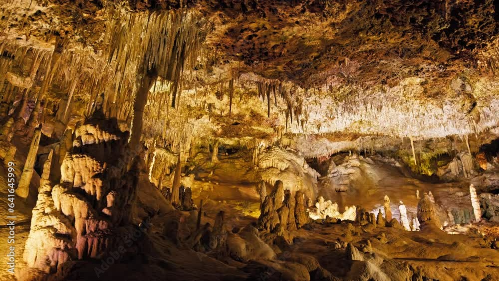 Underground cave with distinct rocky formations of stalactites and stalagmites. A colourful natural scenery in a cave with ancient cavities formed of carbonate limestone rocks in Mallorca, Spain. Underground cave with distinct rocky formations of stalactites and stalagmites. A colourful natural scenery in a cave with ancient cavities formed of carbonate limestone rocks in Mallorca, Spain.
