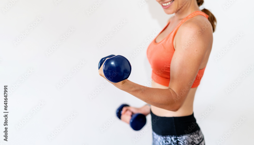 Slim sporty woman wearing sportswear doing biceps exercise using dumbbells. Weight training. Slim sporty woman wearing sportswear doing biceps exercise using dumbbells. Weight training.