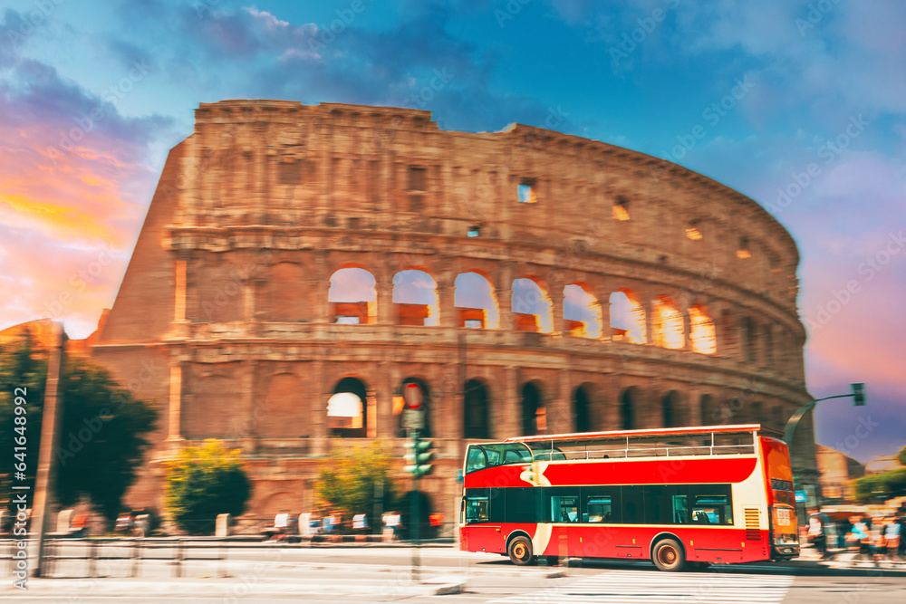 Rome, Italy. Amazing Scenic View Colorful Sky Above Colosseum. Red Hop On Hop Off Touristic Bus For Sightseeing In Street Near Flavian Amphitheatre. Famous World Unesco Landmark. City Sightseeing Tour
