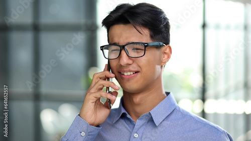 Businessman making a phone call while standing in the lobby of a modern office