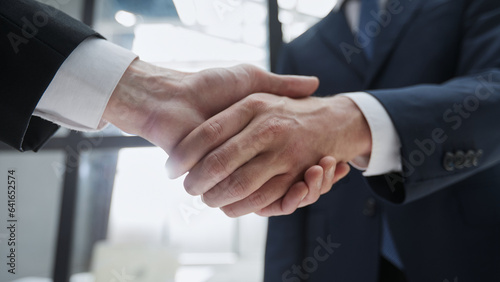 Close up of handshake on blurry conference room interior background. Partnership concept