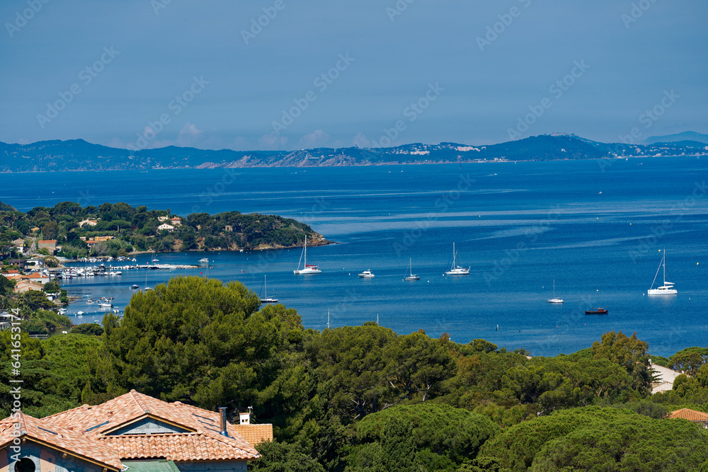 Aerial view of Mediterranean Sea seen from viewpoint of village of Giens with moored sailing boats and mountain panorama on a sunny late spring day. Photo taken June 8th, 2023, Giens, France.
