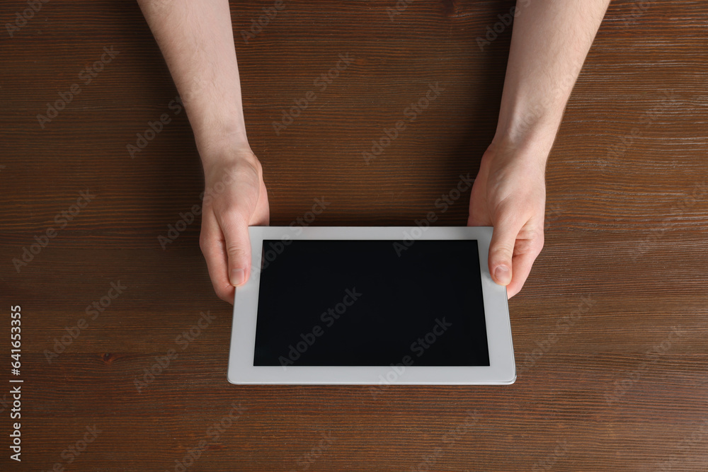 Man working with tablet at wooden table, top view Man working with tablet at wooden table, top view