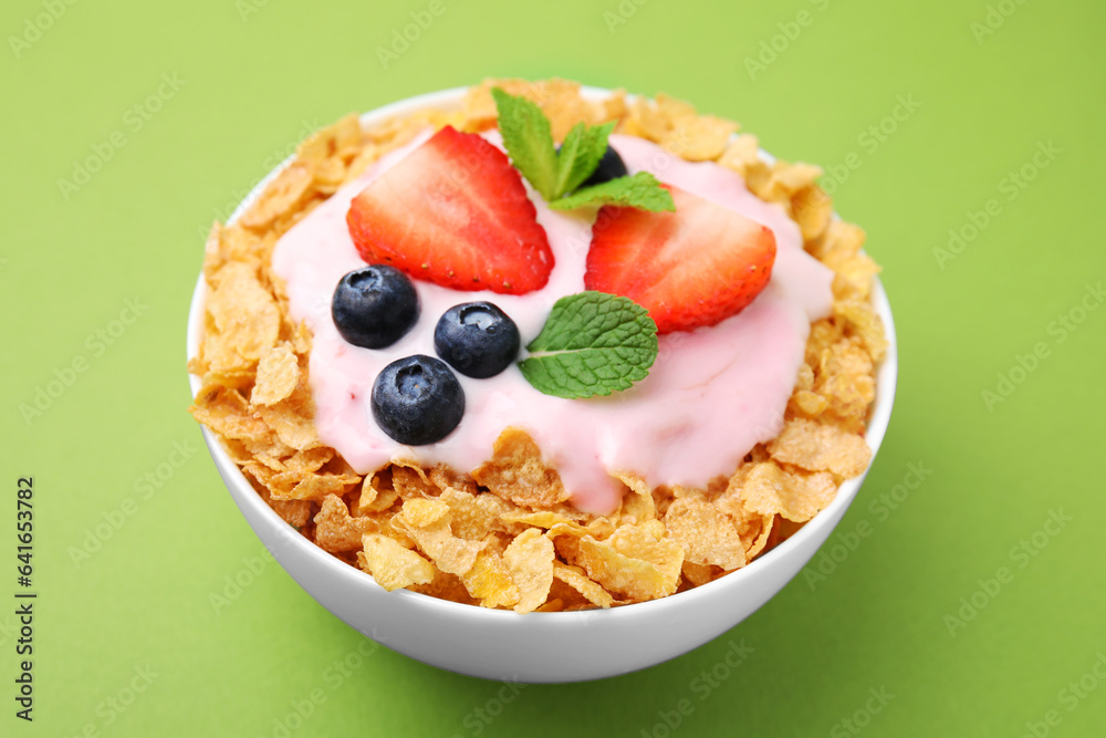 Delicious crispy cornflakes, yogurt and fresh berries in bowl on green background, closeup. Healthy breakfast Delicious crispy cornflakes, yogurt and fresh berries in bowl on green background, closeup. Healthy breakfast