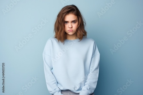 Sadness European Girl In A Blue Sweatshirt On Pastel Background. Сoncept Sadness, European Girl, Blue Sweatshirt, Pastel Background