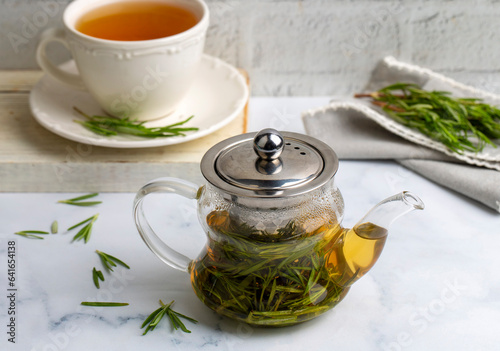 Cup of healthy rosemary tea with fresh rosemary bunch on rustic background, winter herbal hot drink concept, salvia rosmarinus photo