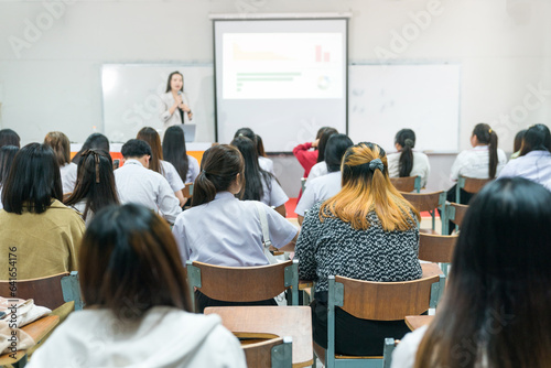 Education, teaching, learning concept. Rear view of college students listening to the lecture in the classroom