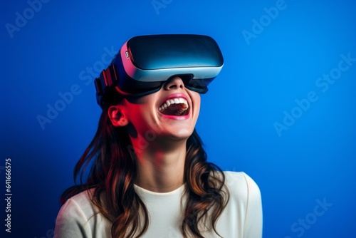 Close-up portrait photography of a happy girl in her 20s playing with virtual reality mask against a royal blue background. With generative AI technology © Markus Schröder