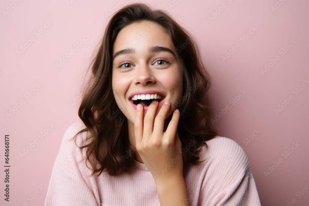 Close-up portrait photography of a grinning girl in her 20s covering his mouth against a pastel pink background. With generative AI technology Close-up portrait photography of a grinning girl in her 20s covering his mouth against a pastel pink background. With generative AI technology