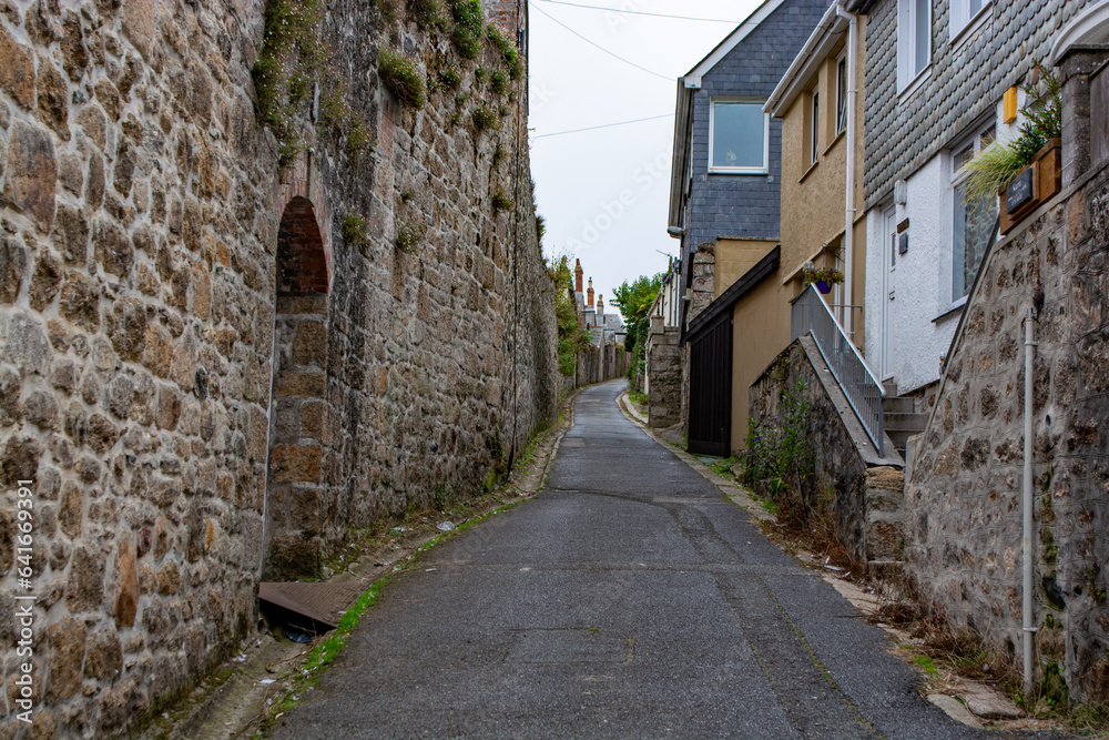 Narrow street with traditional stone houses in a coastal town of St Ives, Cornwall, United Kingdom .