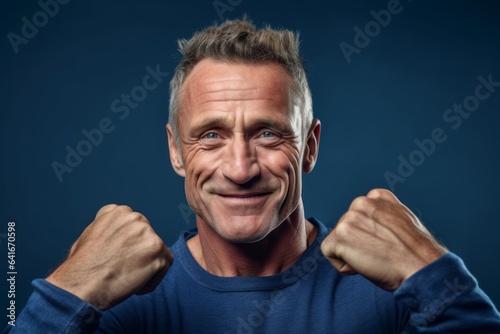 Close-up portrait photography of a happy mature man making a i'm strong gesture showing muscles against a deep indigo background. With generative AI technology
